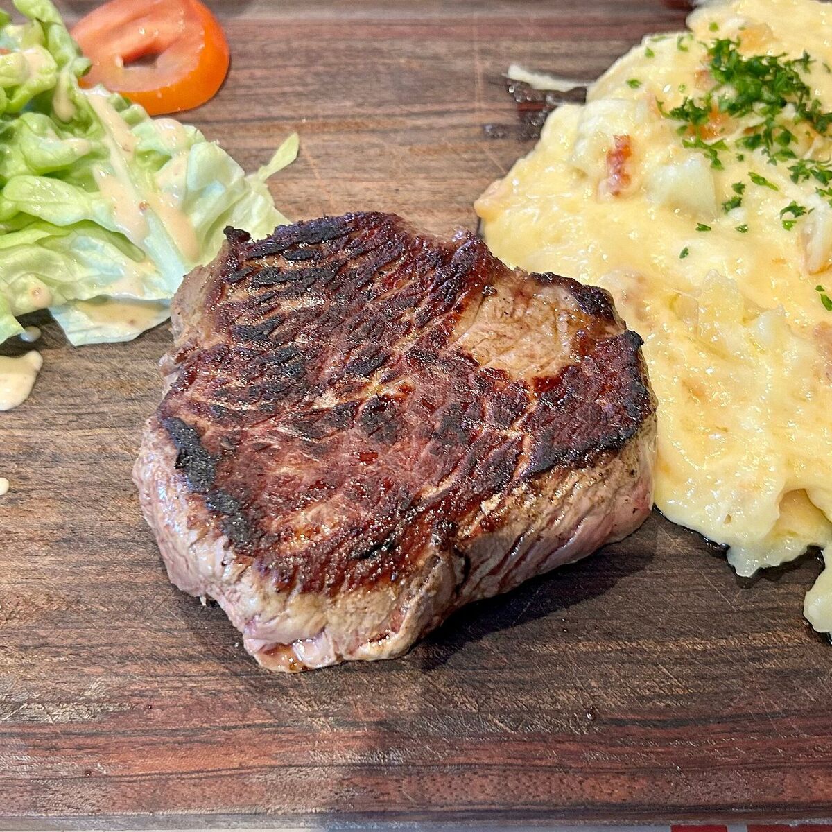 Pièce de boeuf grillée et aligot, servies sur planche